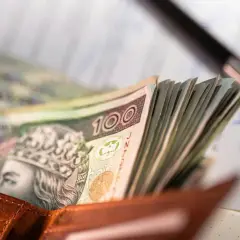Portfel z polskimi banknotami 100 zł, długopis i dokumenty.