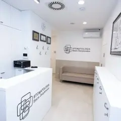 Recepcja nowoczesnej kliniki stomatologicznej z kanapą i logo.