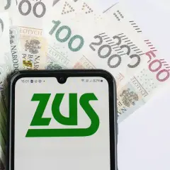 Smartfon z logo ZUS na tle polskich banknotów 100, 200 i 500 zł.