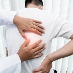 Lekarz bada pacjenta z bólem pod lewą łopatką.
