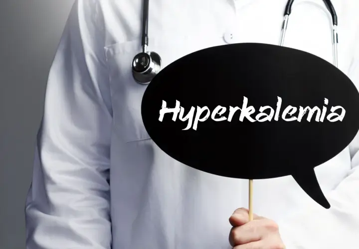 Lekarz w białym fartuchu ze stetoskopem trzyma czarną chmurkę z napisem "Hyperkalemia".