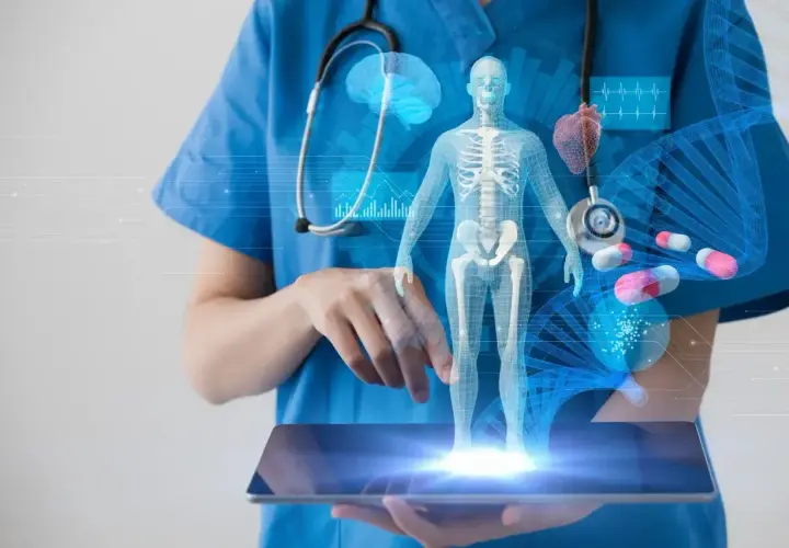 Lekarz w niebieskim fartuchu trzyma tablet z hologramem ludzkiego ciała, organów i DNA.
