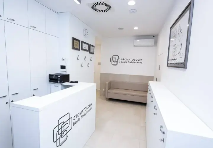 Recepcja nowoczesnej kliniki stomatologicznej z kanapą i logo.