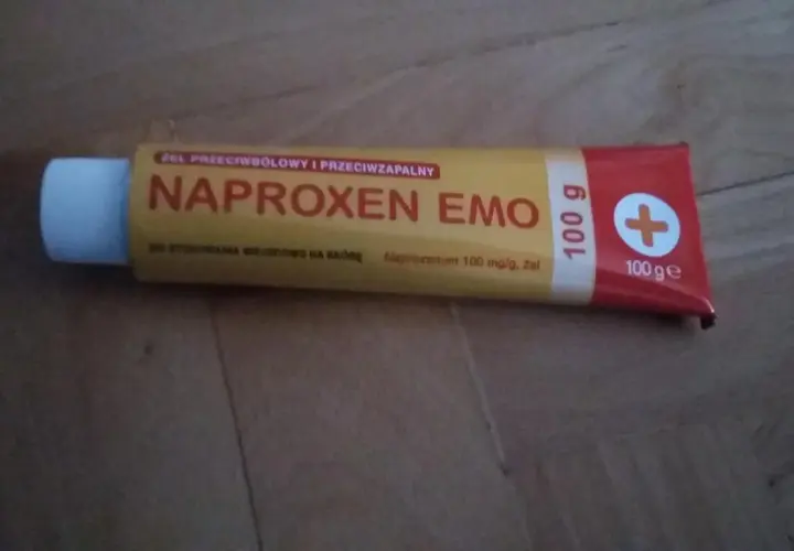 Tuba żelu Naproxen Emo 100g z białym zamknięciem na drewnianym tle.