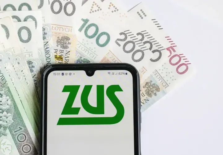 Smartfon z logo ZUS na tle polskich banknotów 100, 200 i 500 zł.