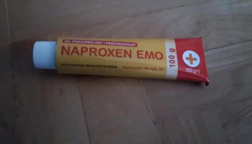Tuba żelu Naproxen Emo 100g z białym zamknięciem na drewnianym tle.