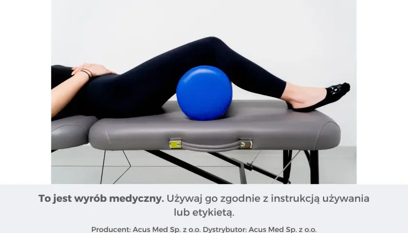 Osoba leżąca na kozetce z niebieską piłką pod kolanami.